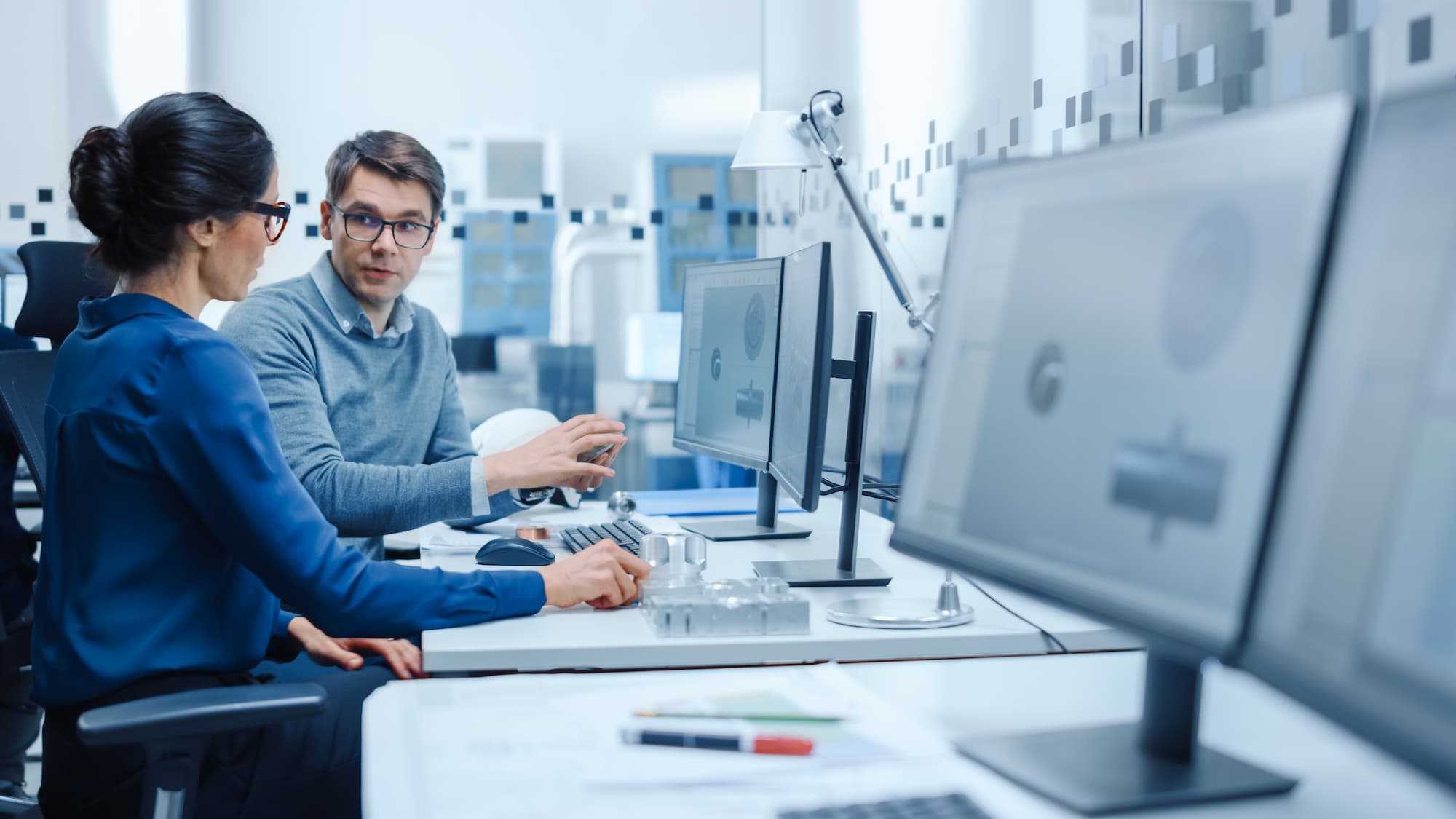 Two people discussing a project plan at their computers