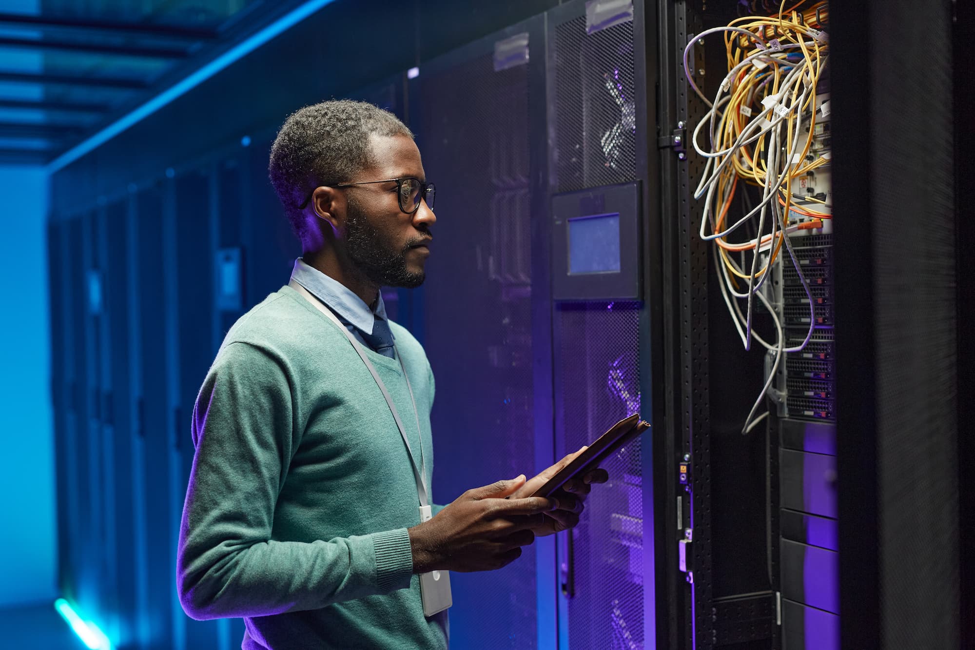 IT service technician with tablet looking at cables