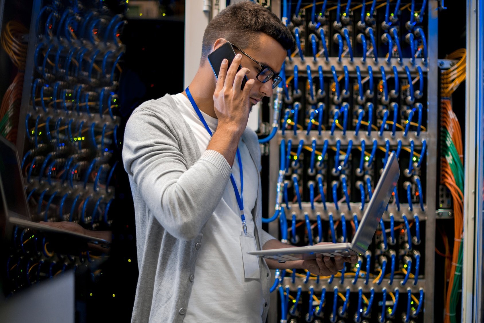 IT service technician in a Server Room on the phone holding a laptop