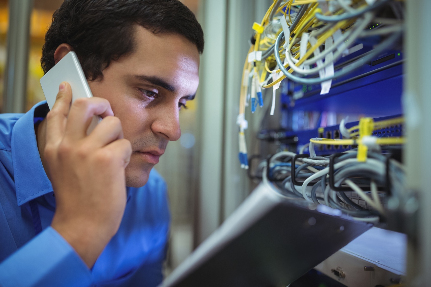 Site Survey technician on phone with tablet and server wiring