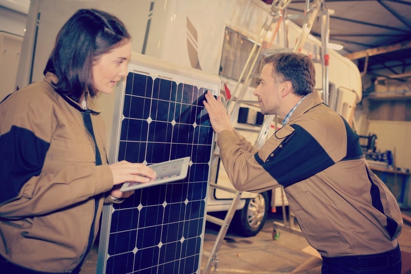 woman technician reading a service manual while another technician performs service