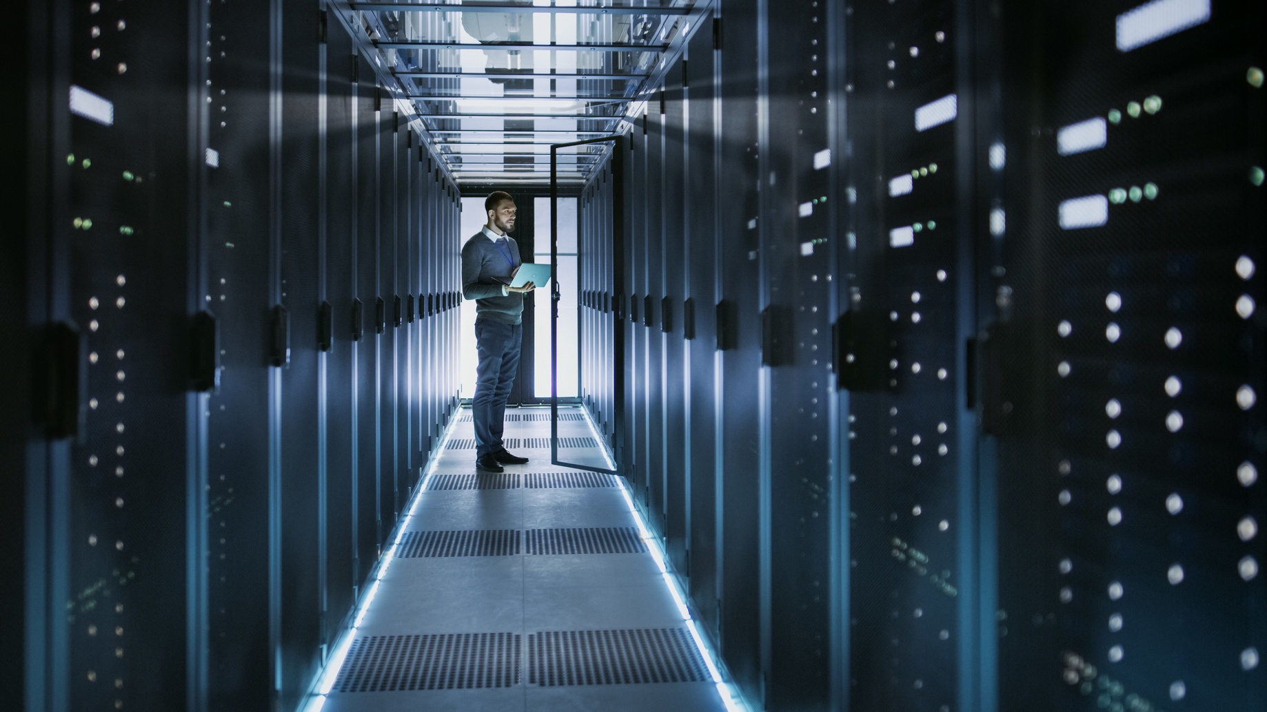 global field technician in hallway with tablet and servers